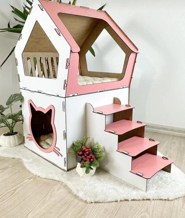 Maison pour chat en bois blanc et rose avec escalier intégré et espace de couchage confortable.